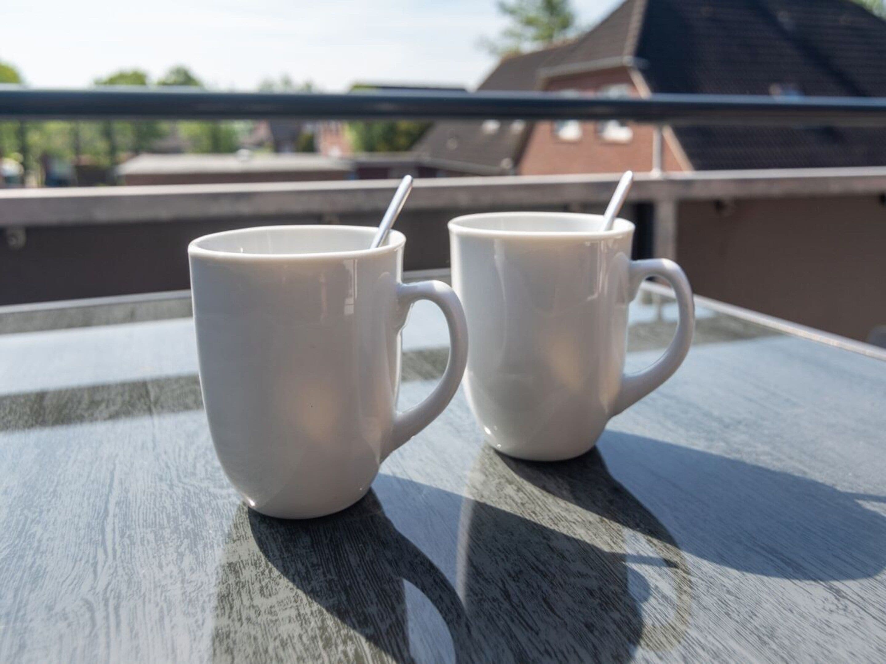 Due tazze di ceramica bianca su un balcone con ringhiera in metallo.