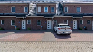 A row of brick buildings with a white car parked in front. - Holiday Home With 1 Bedroom (Esens)