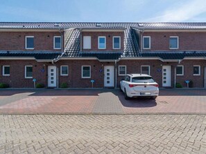 A row of brick buildings with a white car parked in front. - Holiday Home With 1 Bedroom (Esens)