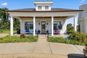 A two-story house with a covered porch, a front door, and two windows on the upper floor.