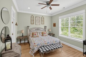 A bedroom with a bed, a ceiling fan, a window with blinds, and a wooden floor.