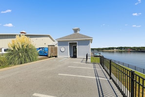 A waterfront property with a small building, a parking area, and a river.