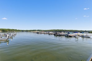 A marina with boats docked, calm water, and a clear sky.