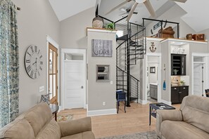 A spacious living area with a staircase leading to a loft, a kitchen, and a dining area.