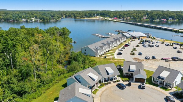 A marina with docked boats, a parking lot, and a row of houses with attached garages.