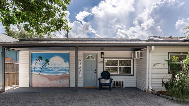 Ein Haus mit einem Strand-Wandgemälde, einem Willkommensschild und der Hausnummer 1035 an der Tür.