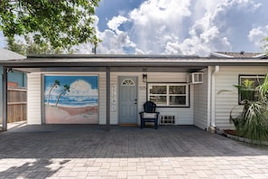 Una casa con un mural de playa, un cartel de bienvenida y el número 1035 en la puerta.