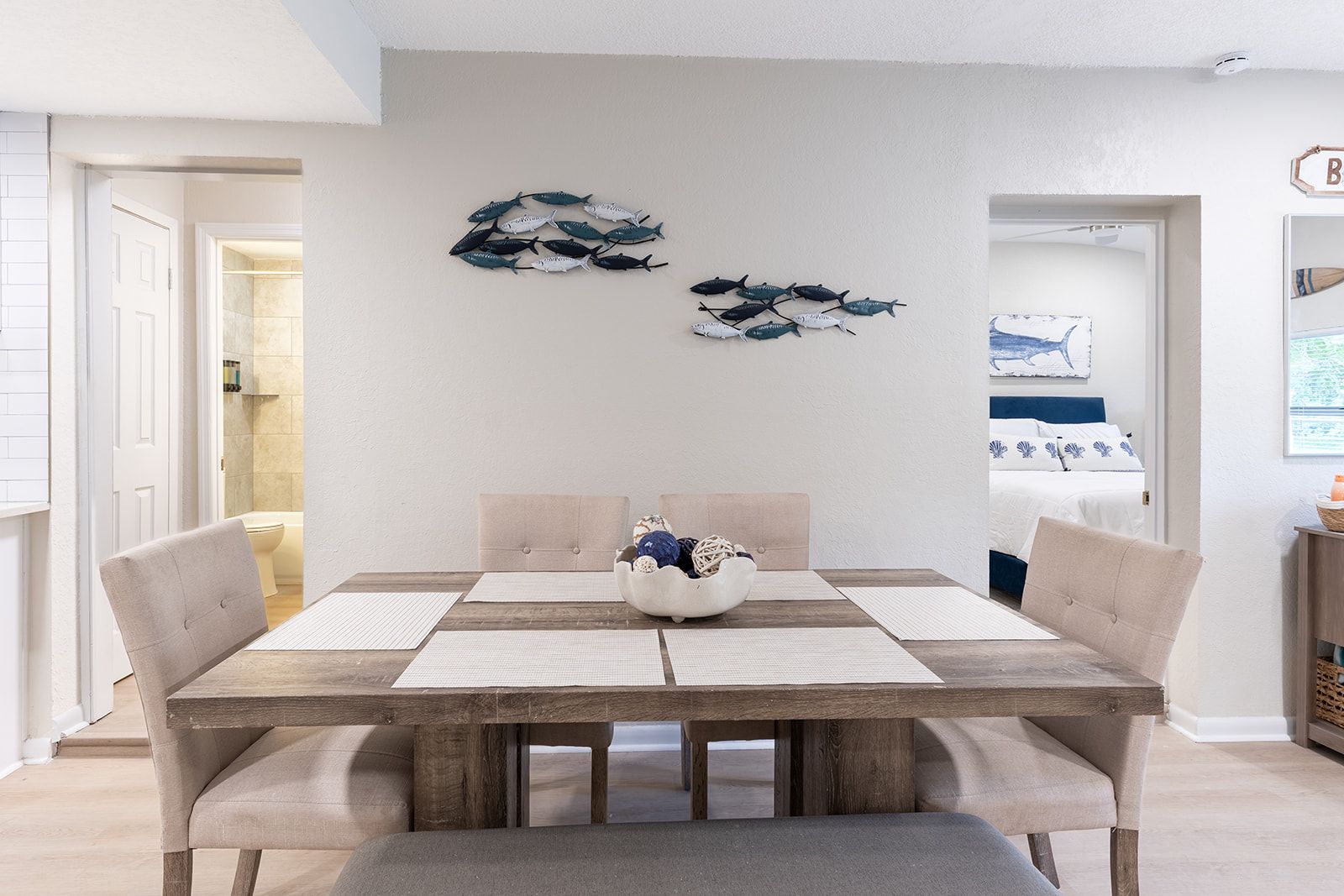 A dining area with a wooden table, cushioned chairs, and a decorative bowl.