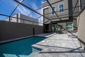A modern outdoor pool area with a clear blue pool, a patio with seating, and a view of the sky. - Doppio Westside home, 15min Disney, pool (Kissimmee)