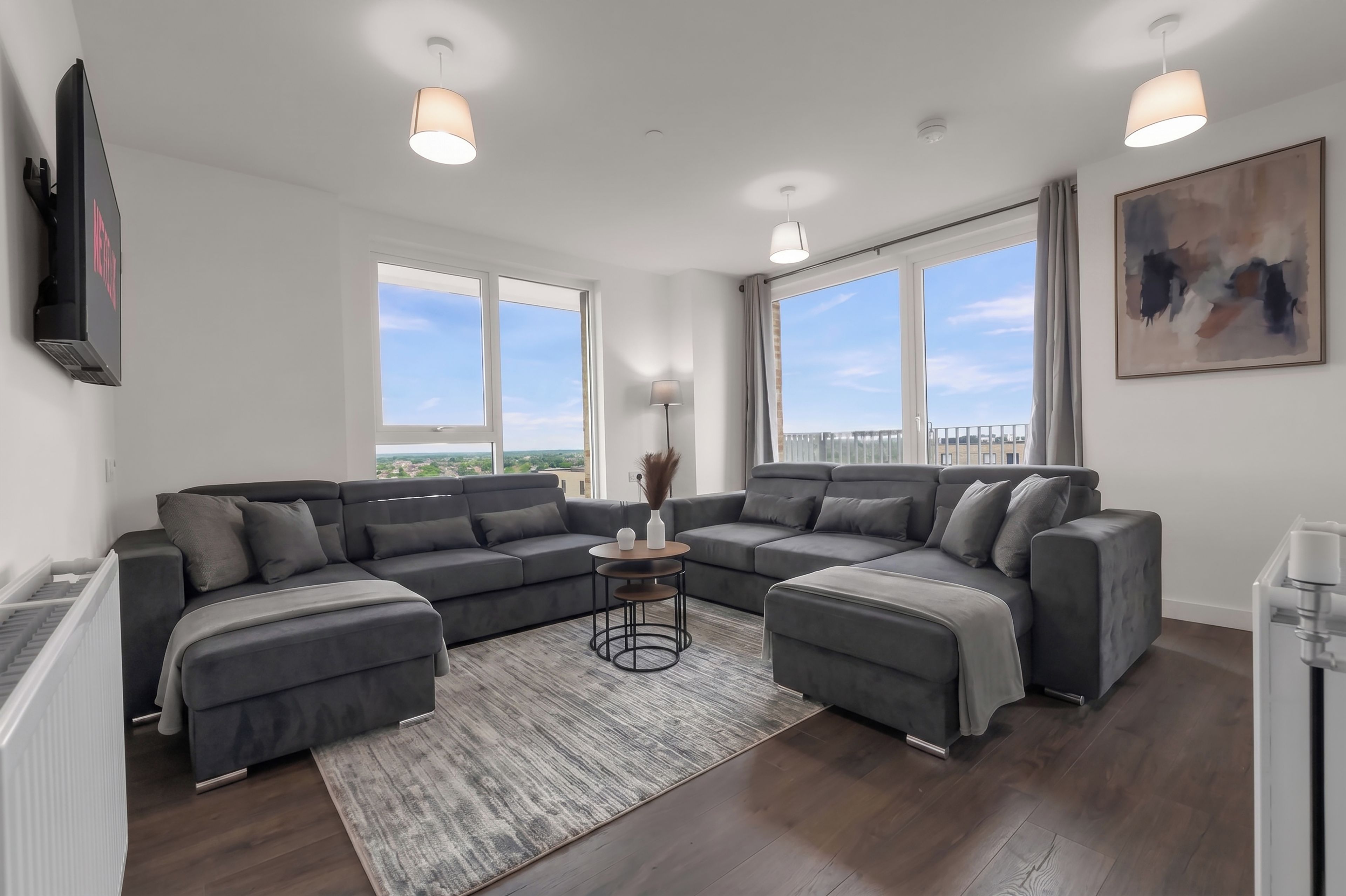A modern living room with a sectional sofa, a coffee table, and large windows offering a view.