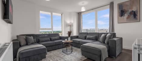 Una sala moderna con un sofá modular, una mesa de centro y ventanas amplias con vistas.