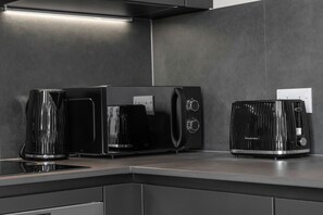 Eine Küche mit modernem Design, inklusive einer schwarzen Kaffeemaschine, eines schwarzen Toasters und eines schwarzen Wasserkochers auf einer Arbeitsplatte.