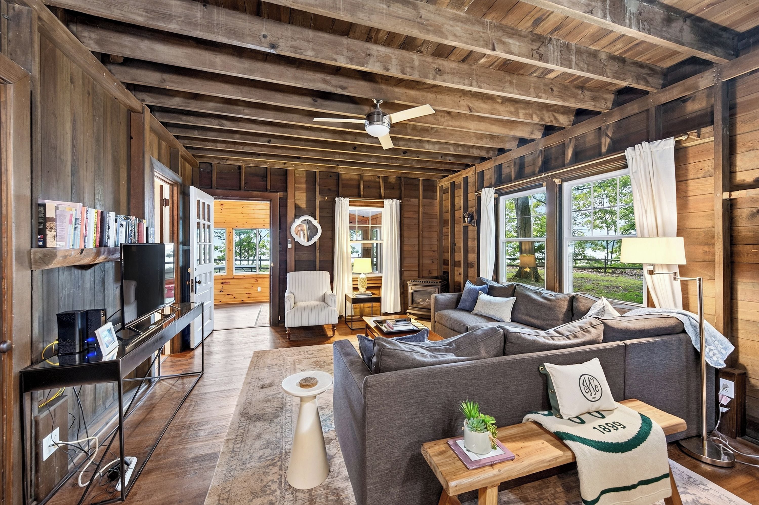 A cozy cabin interior with a sofa, a television, and a fireplace.