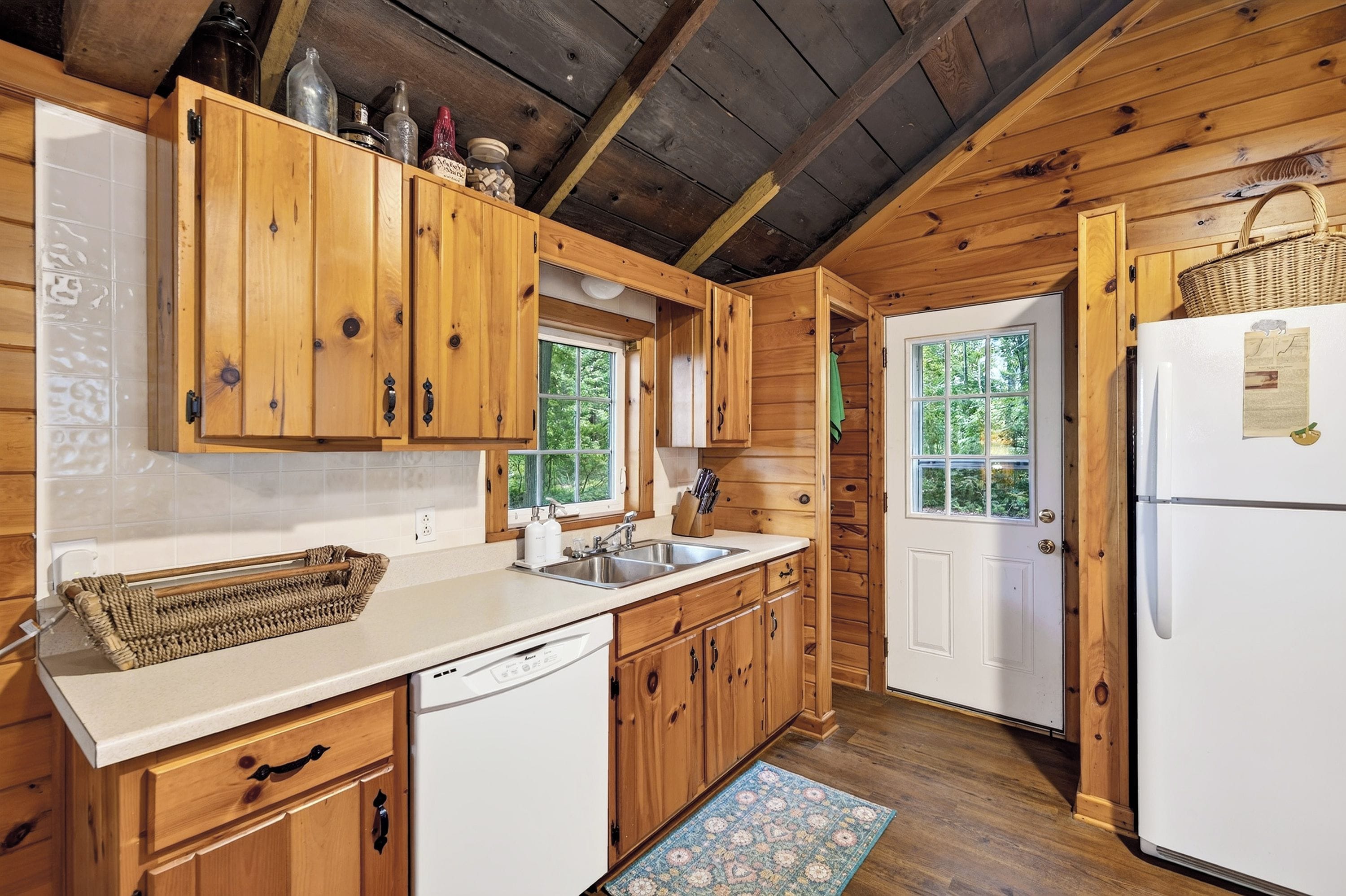 Une cuisine avec des meubles de rangement en bois, un réfrigérateur blanc et une fenêtre.