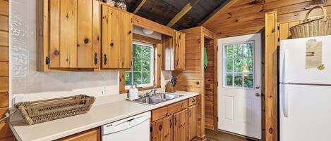 Une cuisine avec des meubles de rangement en bois, un réfrigérateur blanc et une fenêtre.