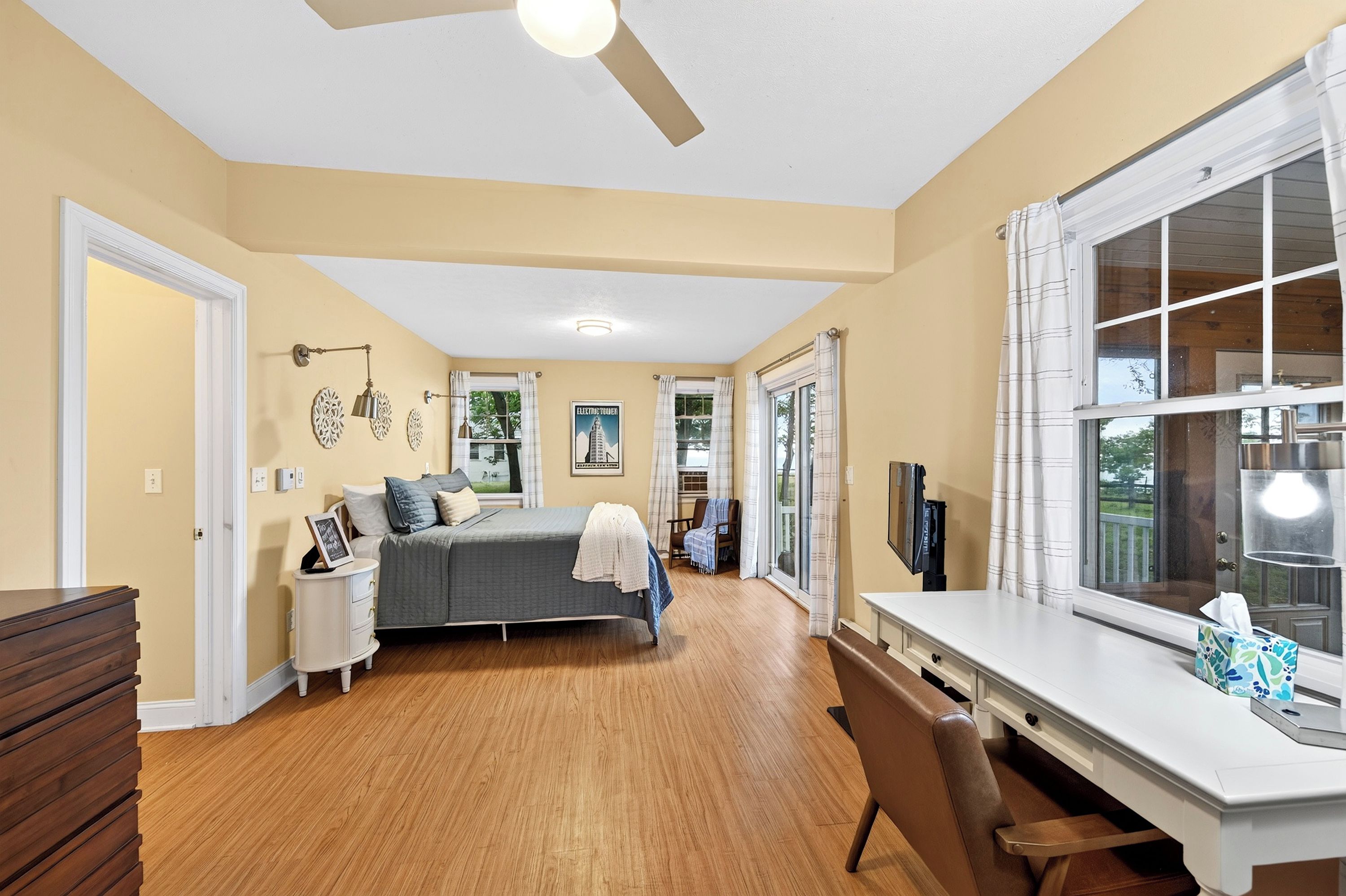 Une chambre à coucher avec un lit, une table de chevet, une commode et une fenêtre avec des rideaux.