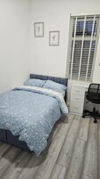 Un dormitorio con cama, escritorio y ventana con persianas.