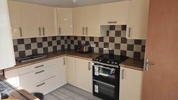 A kitchen with beige cabinets, a black stove, and a checkered backsplash.