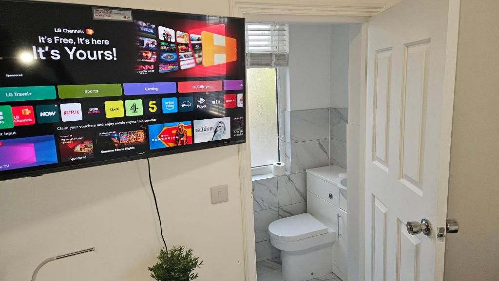 A flat-screen TV mounted on a wall displaying various streaming services and channels.