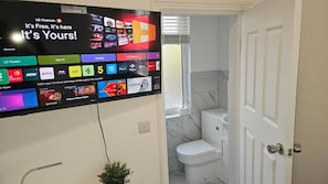 A flat-screen TV mounted on a wall displaying various streaming services and channels.