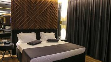 A hotel room with a large bed, a desk, and a modern wall design.