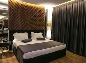 Ein Hotelzimmer mit einem grossen Bett, einem Schreibtisch und einem modernen Wanddesign.