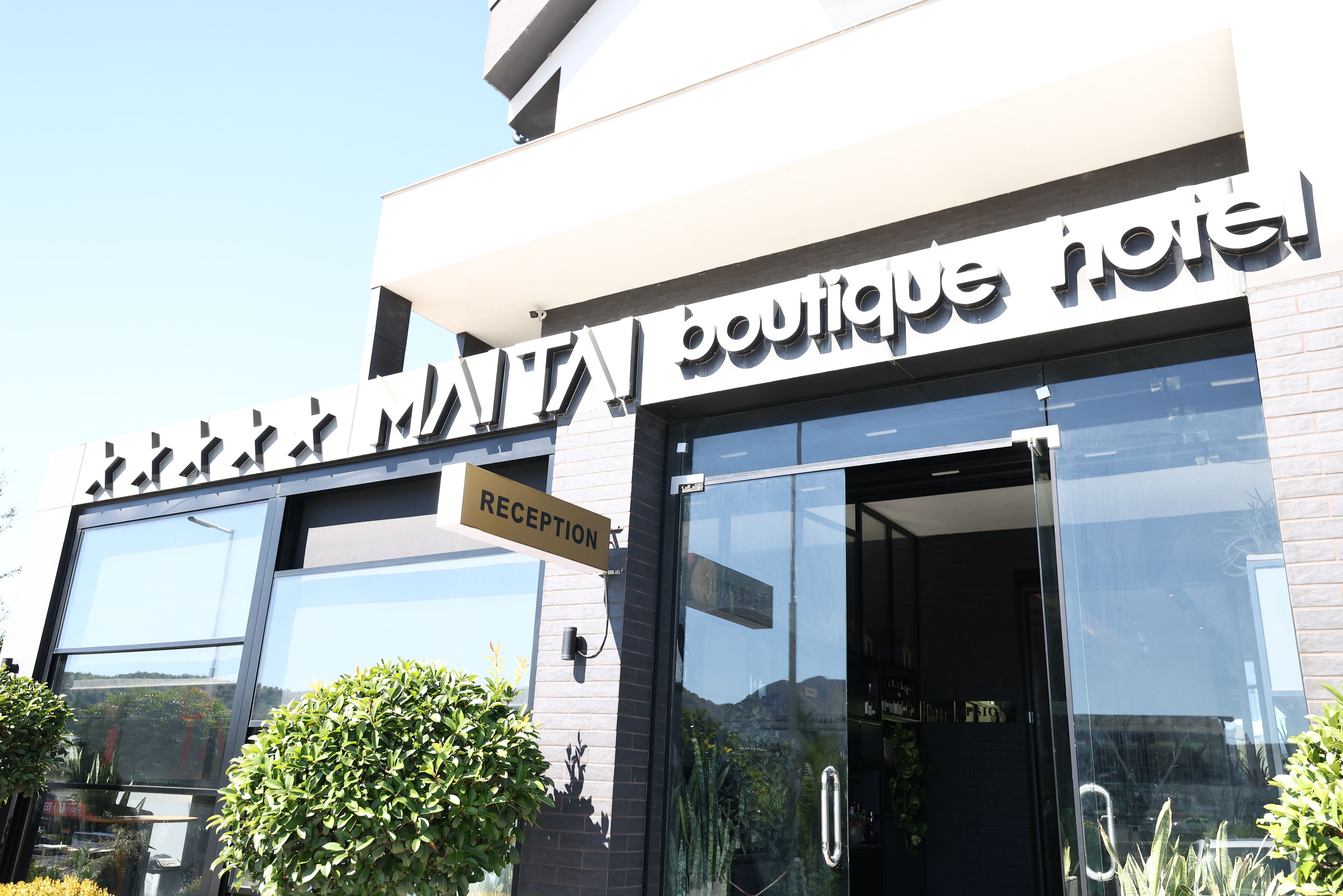 Un hotel boutique con un letrero de recepción y amplias ventanas.