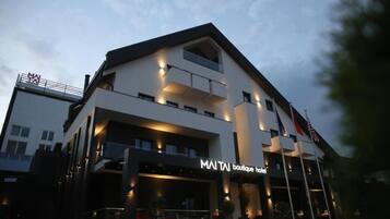 A modern boutique hotel with a prominent sign, multiple balconies, and a well-lit entrance.