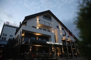 Ein stilvolles Boutique-Hotel mit auffälligem Schild, mehreren Balkonen und einem gut beleuchteten Eingang.