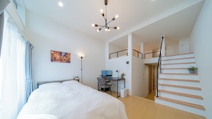 Ein modernes Schlafzimmer mit Bett, Schreibtisch und Treppe.