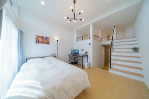 Ein modernes Schlafzimmer mit Bett, Schreibtisch und Treppe.