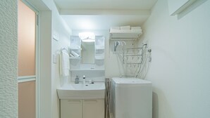 Ein kleines Badezimmer mit Waschbecken, Spiegel, Handtuchhalter und einem kleinen Stauraumschrank.