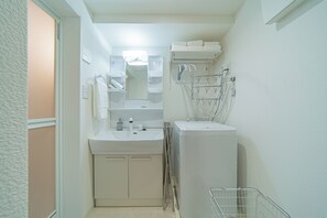Ein kleines Badezimmer mit Waschbecken, Spiegel, Handtuchhalter und einem kleinen Stauraumschrank.