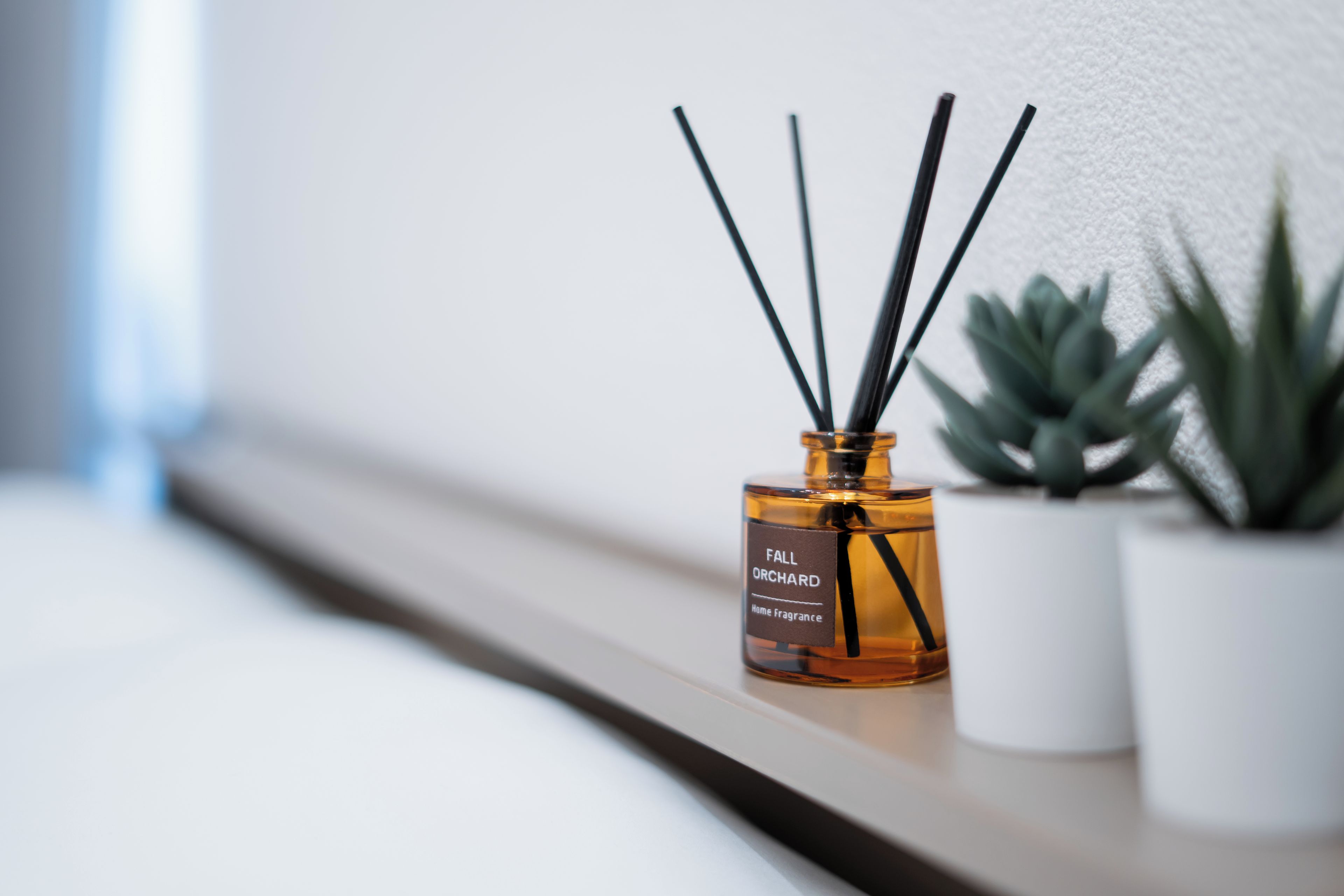 A bottle of Fall Orchard Home Fragrance with reed diffusers on a shelf.