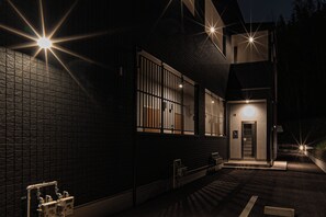 A building with a dark facade, a gated entrance, and a visible elevator. - Forest Side Base (Kumamoto/Higashiku/Kozono)