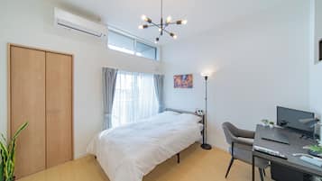 A modern bedroom with a bed, desk, and computer.