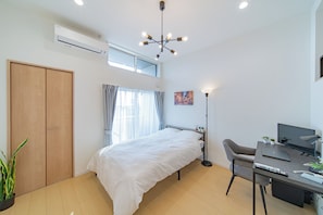 Ein modernes Schlafzimmer mit Bett, Schreibtisch und Computer.