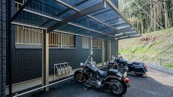 A motorcycle parked under a covered area with a brick wall and a window.