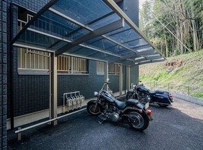 A motorcycle parked under a covered area with a brick wall and a window. - Forest Side Base (Kumamoto/Higashiku/Kozono)