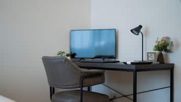 Ein moderner Arbeitsplatz mit Schreibtisch, Stuhl, Computer, Lampe und einer kleinen Pflanze.