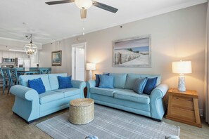 A living room with two light blue sofas, a woven basket, and a painting of a beach scene. - Beachfront Bliss at Fort Walton Beach (Fort Walton Beach)