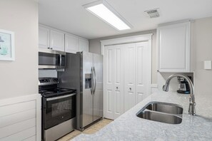A modern kitchen with stainless steel appliances, white cabinetry, and a double sink. - Beachfront Bliss at Fort Walton Beach (Fort Walton Beach)