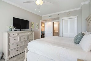 A bedroom with a large bed, a dresser, a television, and a door leading to a bathroom. - Beachfront Bliss at Fort Walton Beach (Fort Walton Beach)