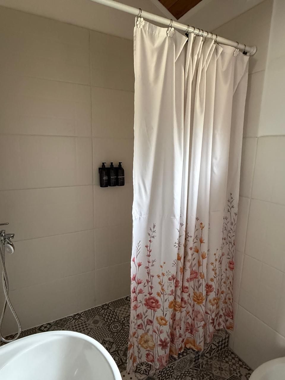 Une salle de bain équipée d’un rideau de douche, d’une baignoire et d’un distributeur de shampoing fixé au mur.