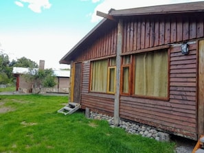 A wooden cabin with a porch, a small step leading to the entrance, and a stone foundation.