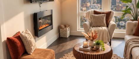 A modern living room with a city view, a fireplace, and a round coffee table.