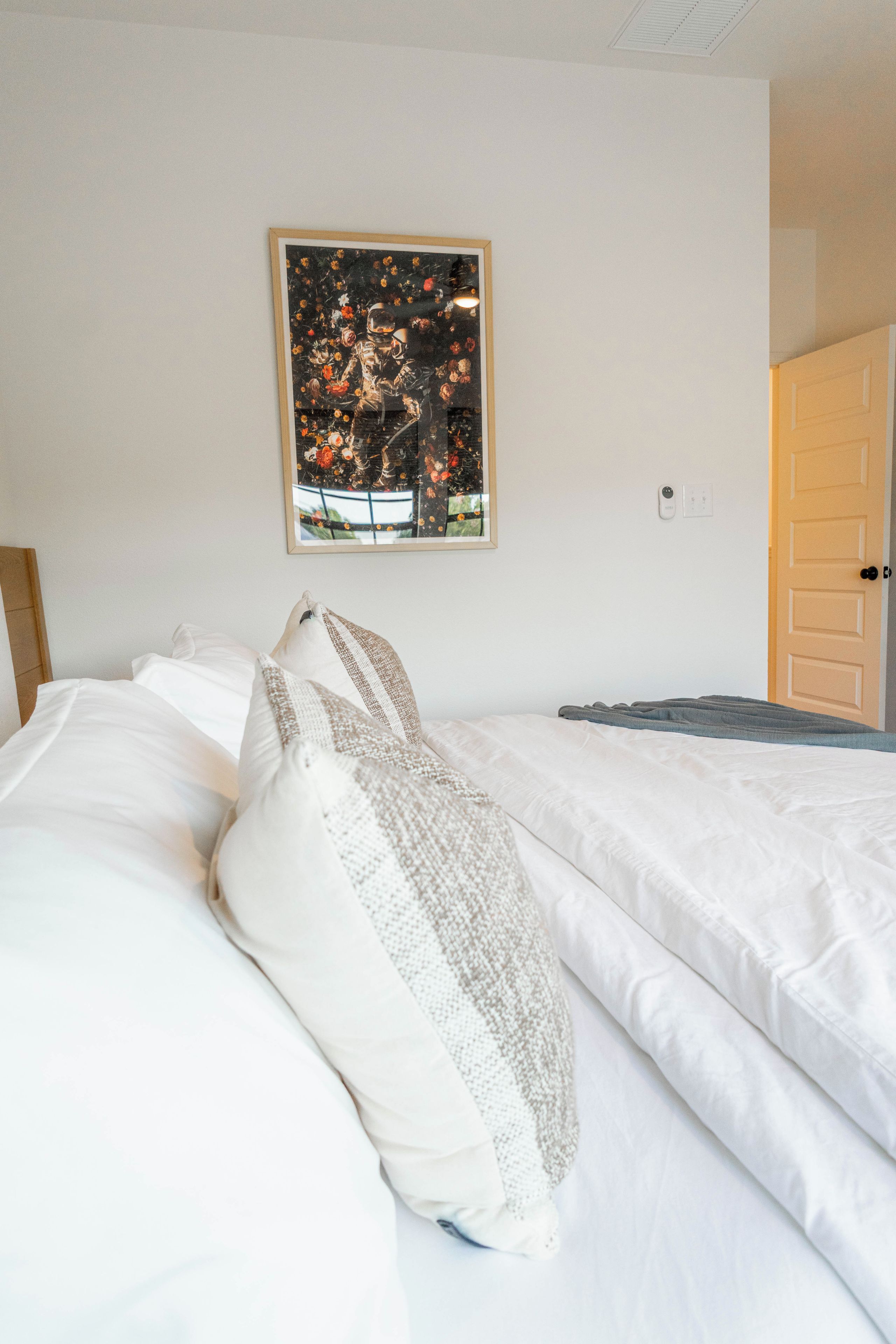 A neatly made bed with white linens and a pillow with a textured pattern.