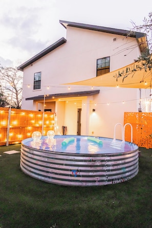 Una casa moderna con piscina, luces colgantes y un patio cubierto.