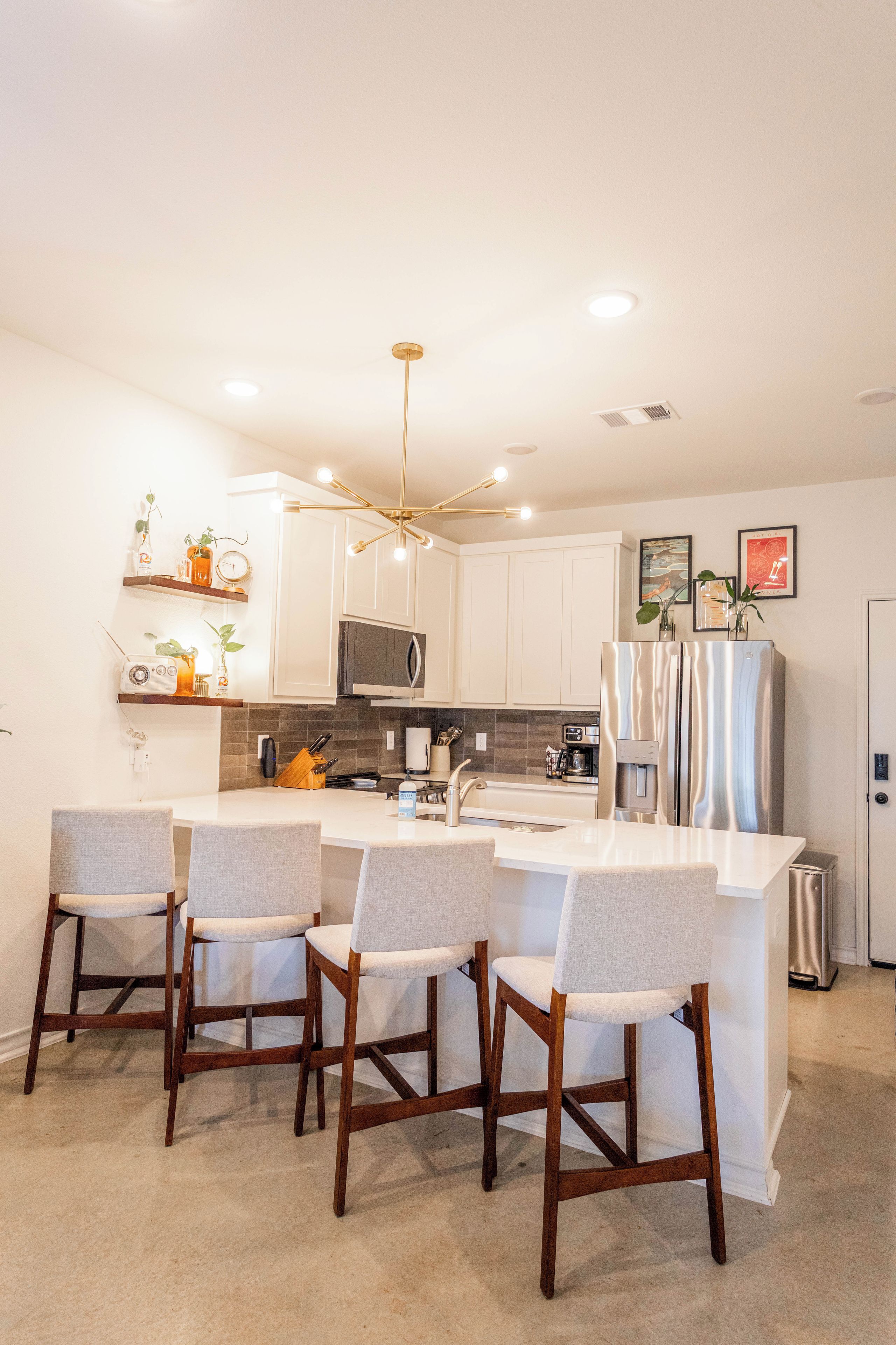 A modern kitchen with a central island, bar stools, and a pendant light.