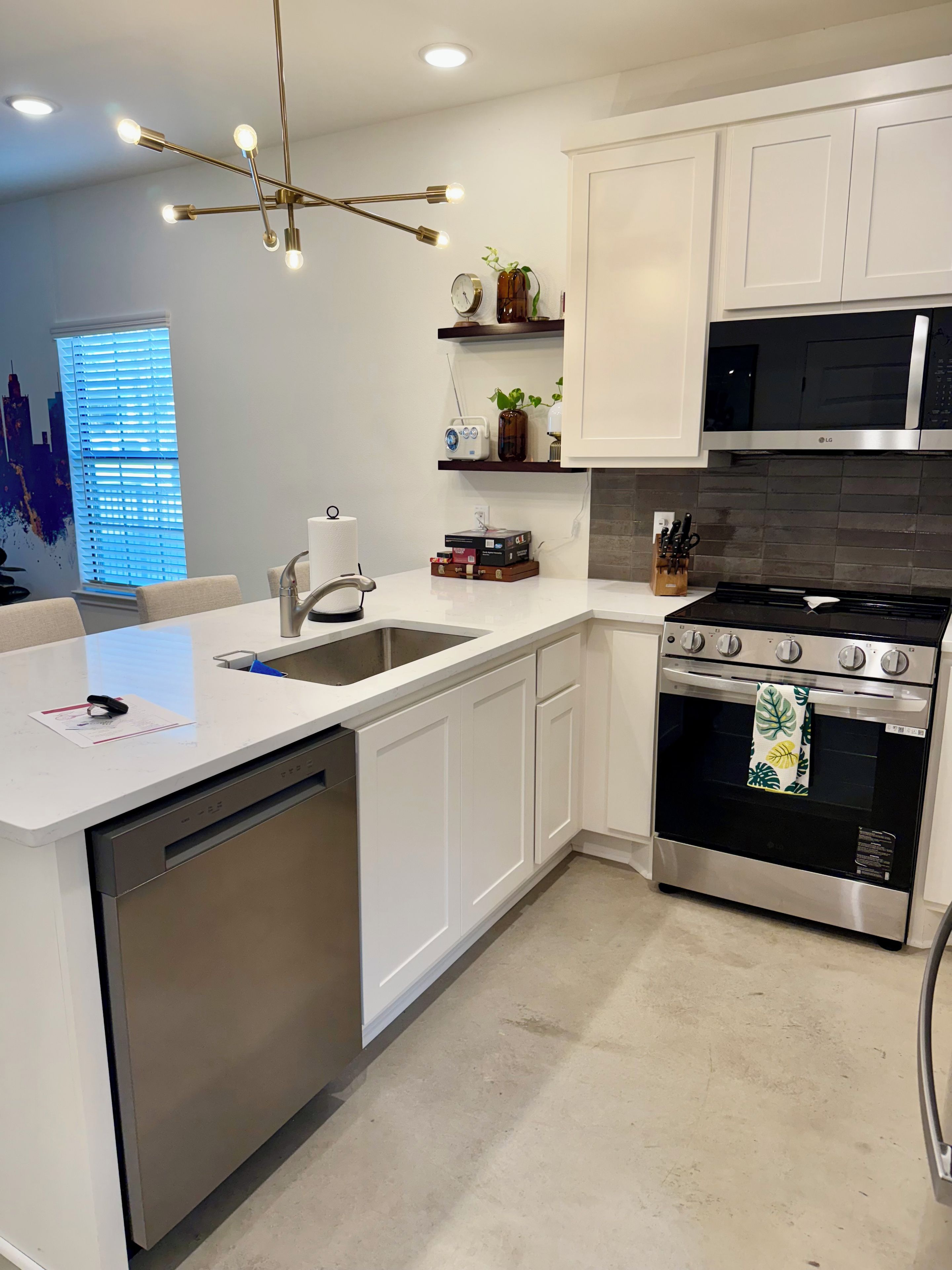 A modern kitchen with white cabinetry, a stainless steel dishwasher, a black stove, and a microwave.